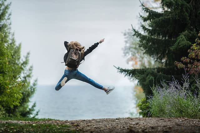 woman-jumping-wearing-green-backpack